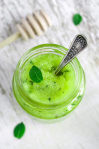 Mint and honey face and body scrub in a small glass jar